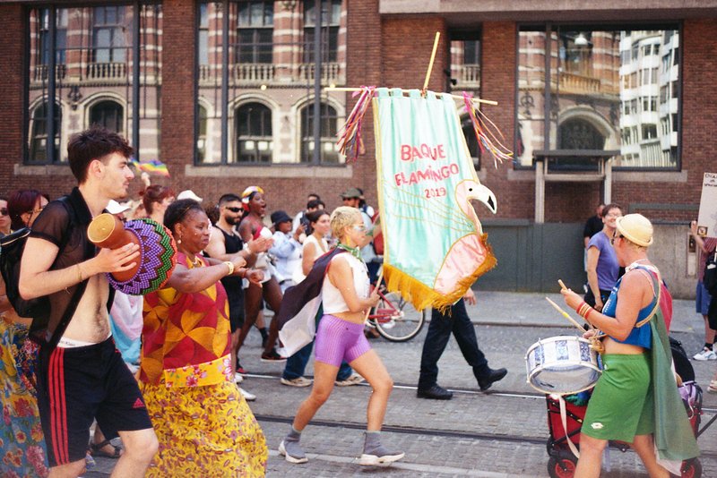This image captures a lively street scene with a group of people participating in what appears to be a parade or festival. In the center of the frame,