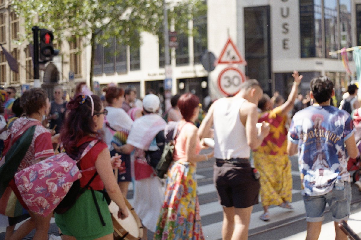 This is a photograph of an outdoor scene where a large group of people is seen walking down the street. The individuals appear to be partaking in a pa