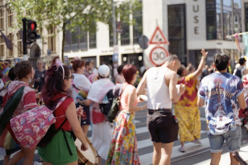 This is a photograph of an outdoor scene where a large group of people is seen walking down the street. The individuals appear to be partaking in a pa