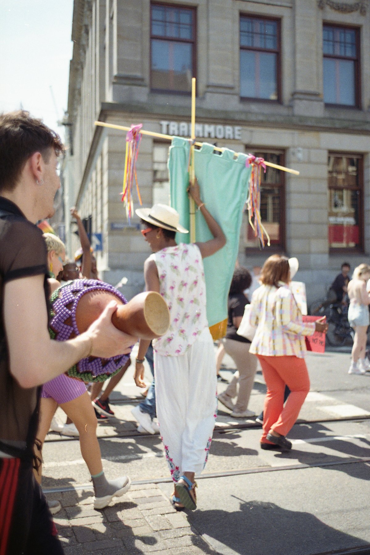 This image depicts a lively scene from a parade. The main focus is on two individuals who are dancing with masks and colorful outfits. One individual 