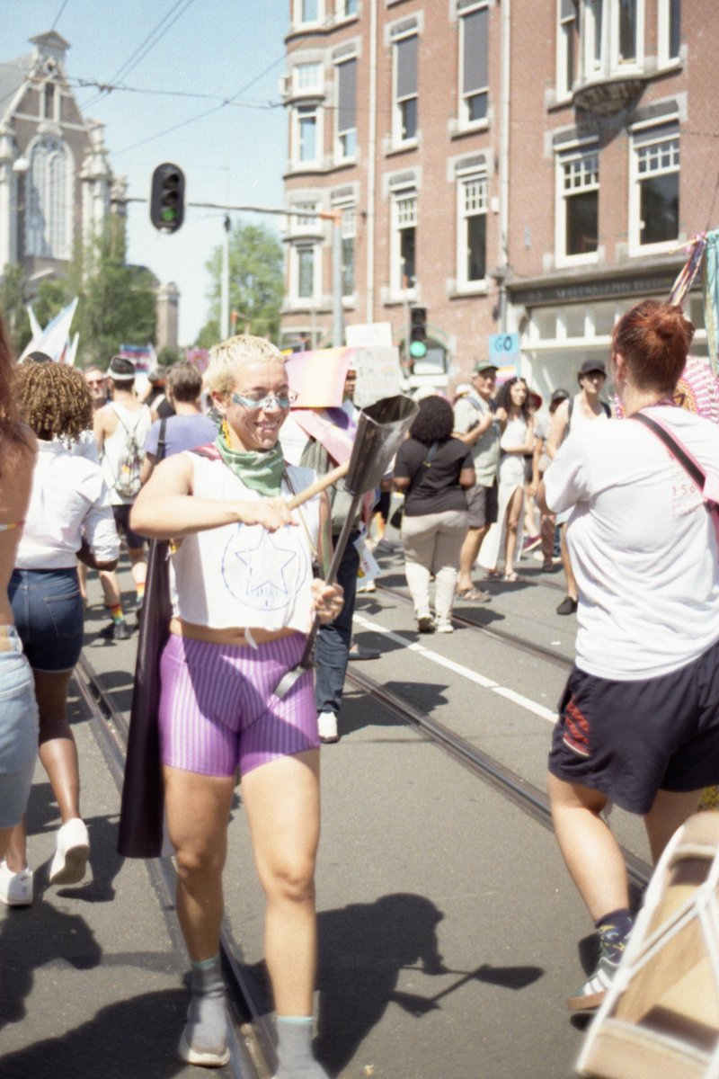 The image depicts a woman jogging in a busy street filled with people. She is wearing a purple and pink shirt, blue shorts, and a face mask. The setti