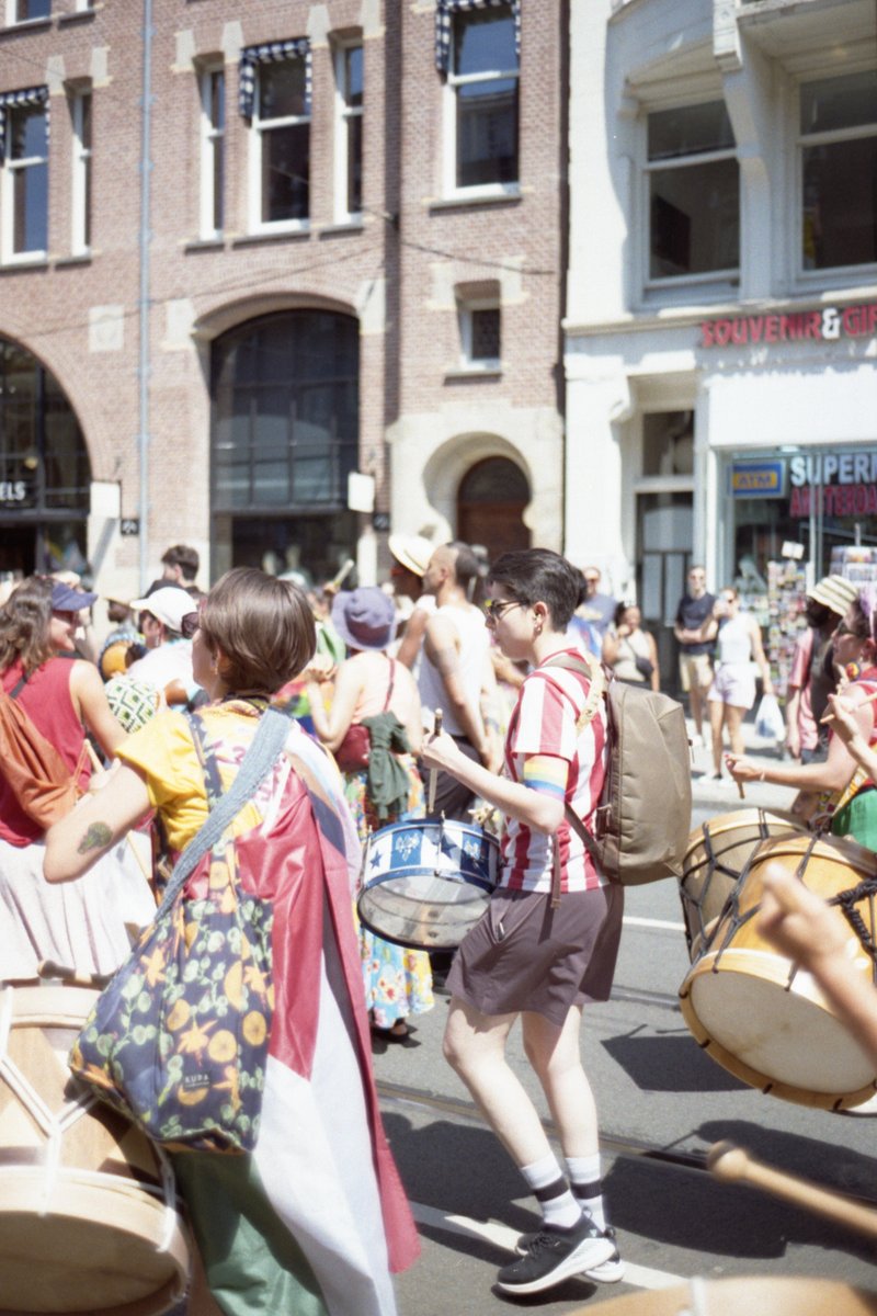 This is a lively street scene where a crowd of people are playing musical instruments. They seem to be enjoying the outdoor festival. The crowd is mix