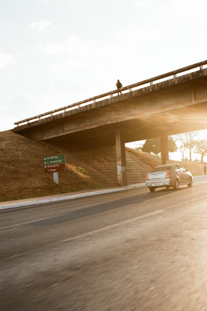 A blurred highway scene with a bridge and an overpass. The sky is visible above the bridge.