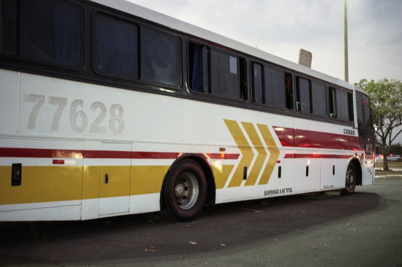 The image displays two pictures of the same scene. Both show a parked transit bus during dusk or nighttime. The bus has yellow markings and the number