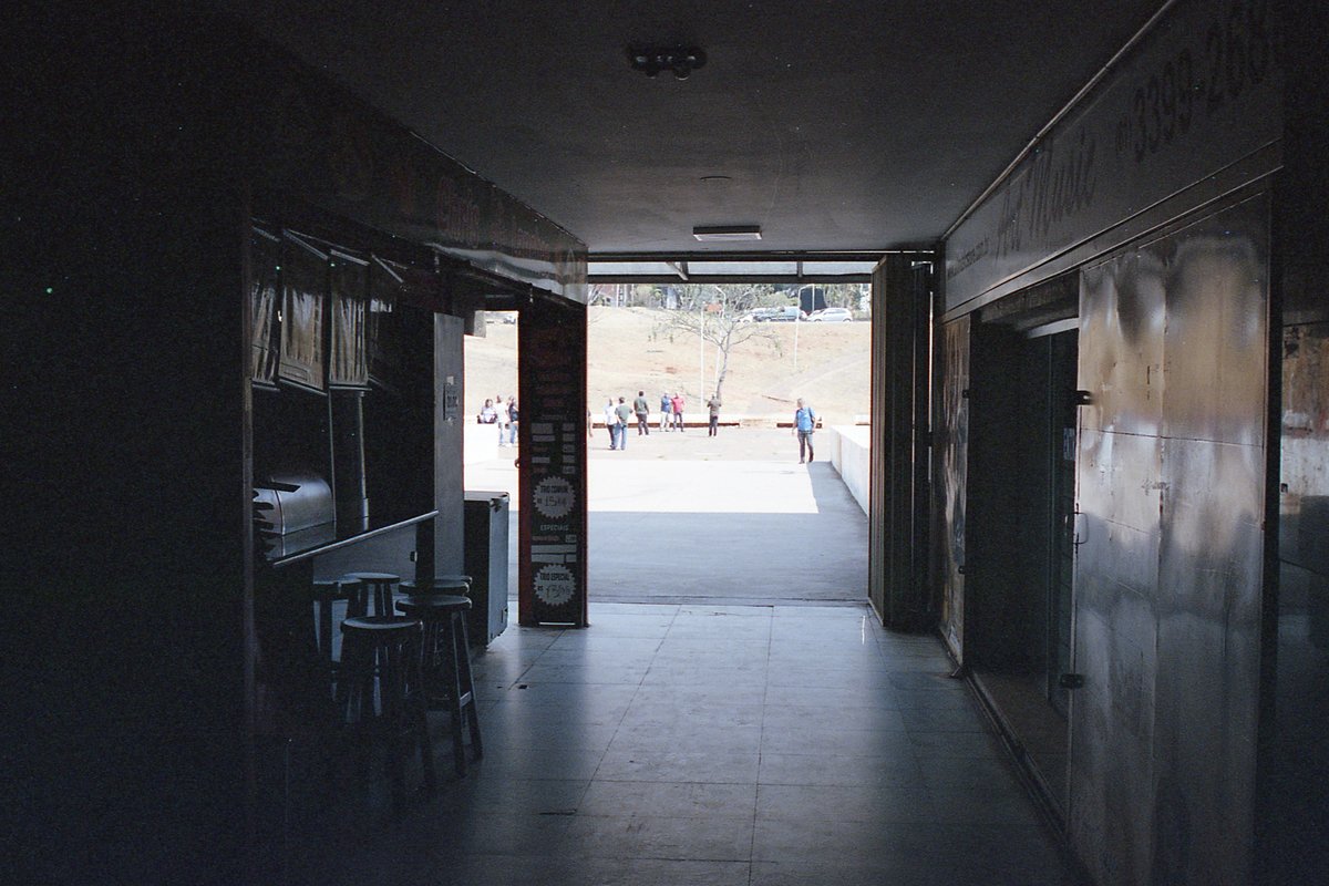 The image depicts an interior scene with a long perspective hallway. The hallway is illuminated by artificial lighting and appears to be part of a bui