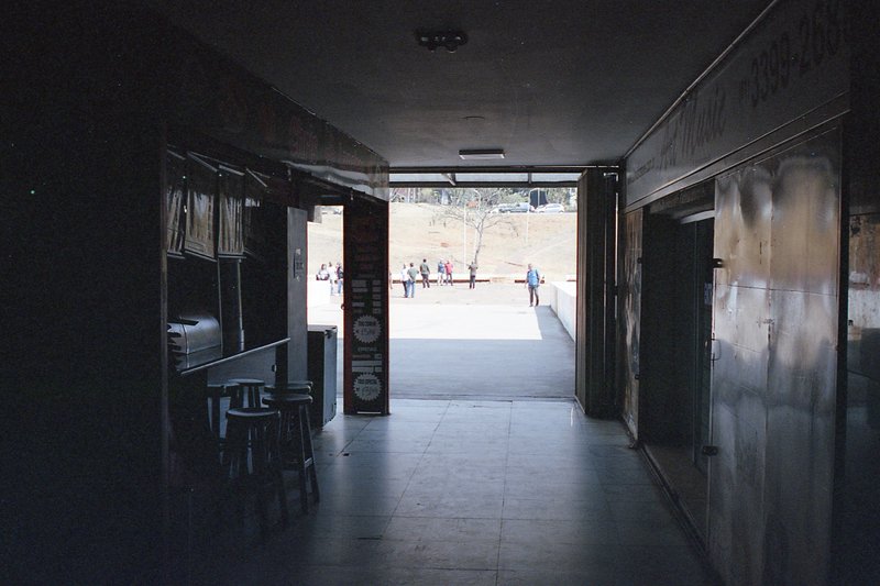 The image depicts an interior scene with a long perspective hallway. The hallway is illuminated by artificial lighting and appears to be part of a bui