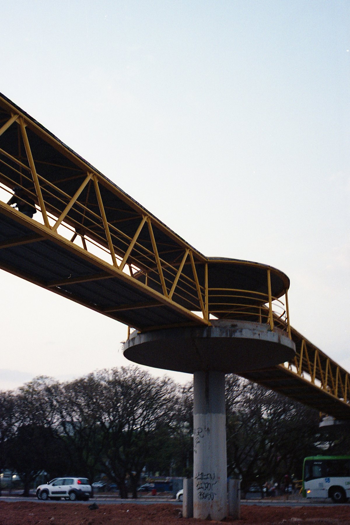 This image depicts a highway overpass with yellow railings. The structure is supported by sturdy concrete pillars and appears to be undergoing constru