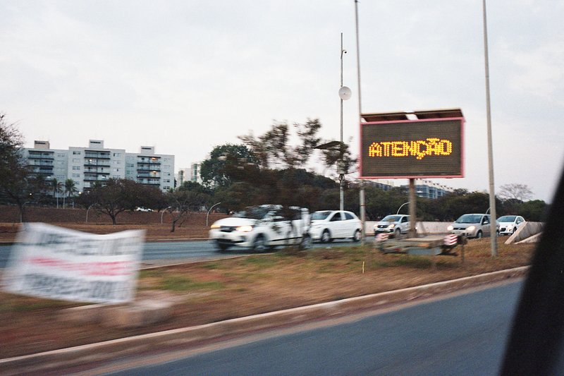 This image captures a street scene. A large sign is prominently featured in the center of the frame, indicating "Atencion". The background reveals a b