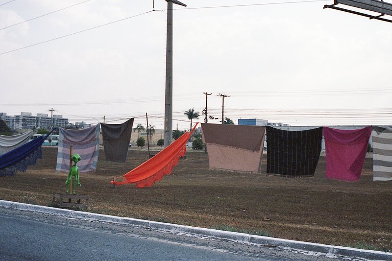 The image shows an outdoor scene of laundry hanging on a clothesline. There are six items of clothing suspended from the line: two shirts, two pants,