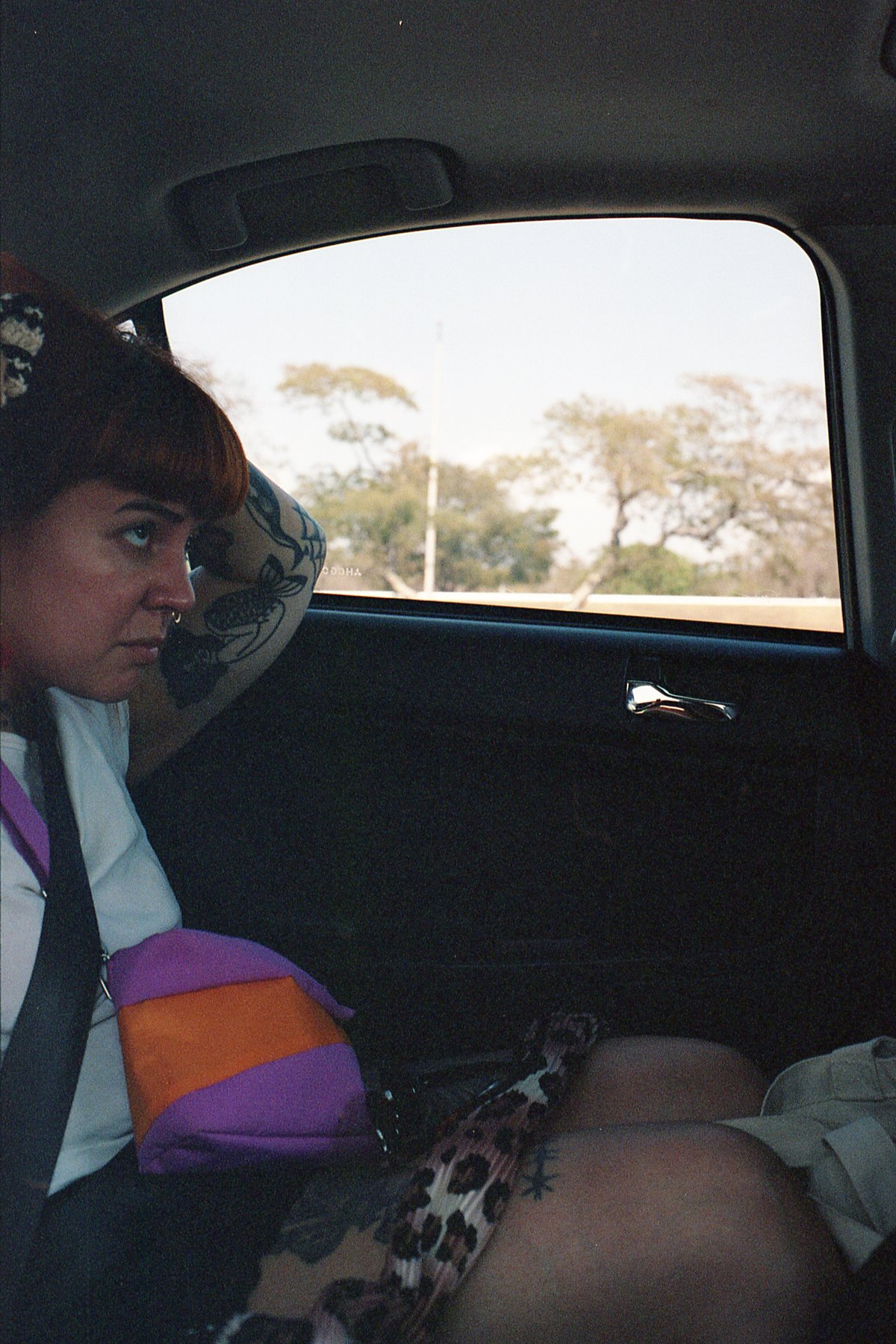 The image is a candid photograph featuring a person seated inside a vehicle. The individual appears to be looking out of the window with their head re