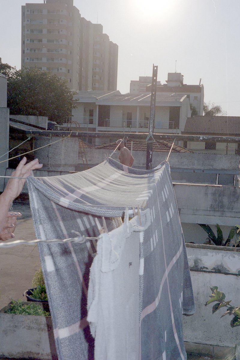 The image shows a person taking a photo of their laundry hanging on a clothesline. The washing is hung out to dry and the sun is shining brightly from