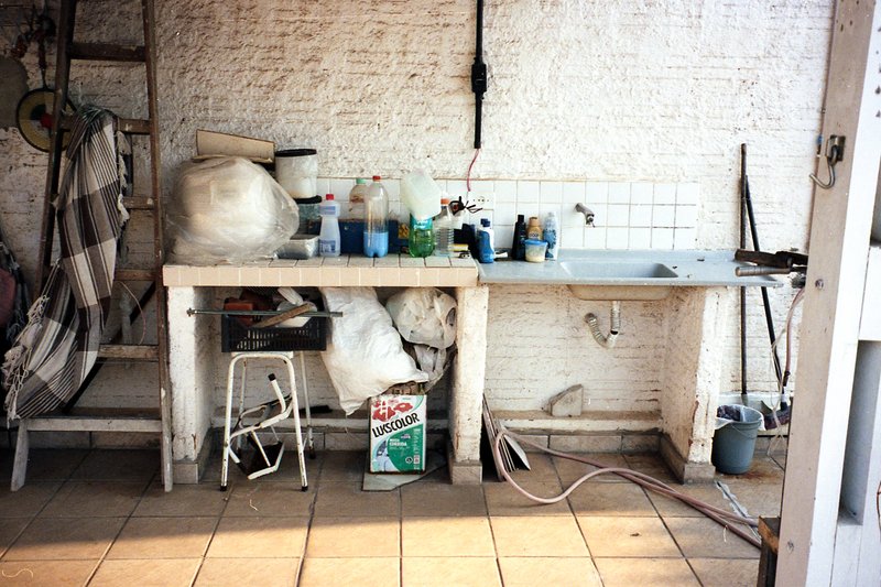 The image shows an interior view of a workshop or garage. There is a long workbench with various tools and items scattered across its surface. On the