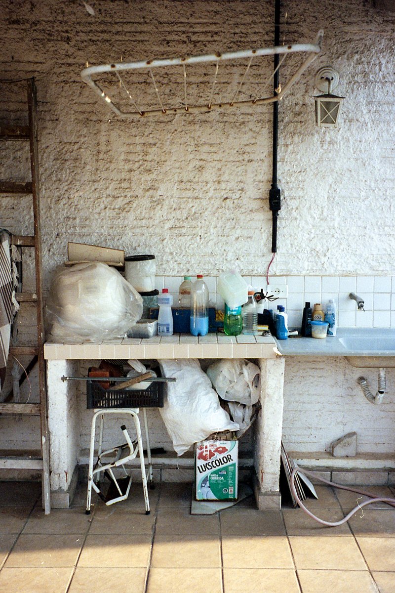 The image depicts the interior of a commercial kitchen. There is a large white metal shelf that spans across one wall, filled with various cooking ute