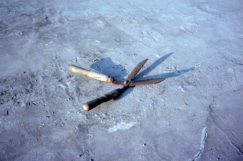 The image showcases a setting of a muddy surface where two knives with wooden handles are placed diagonally, one atop the other. The blades of the kni