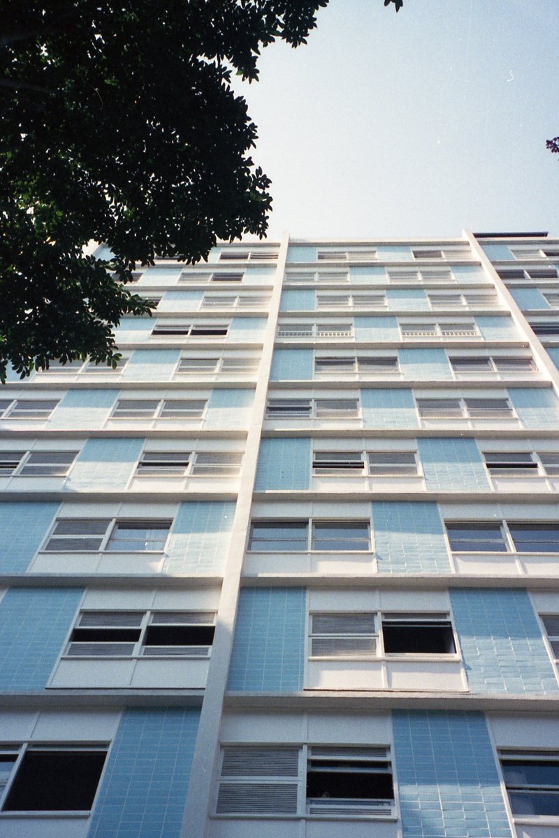 A tall building with blue accents. The building has many windows and is the main subject of the image. There are no people or visible activity. The sk