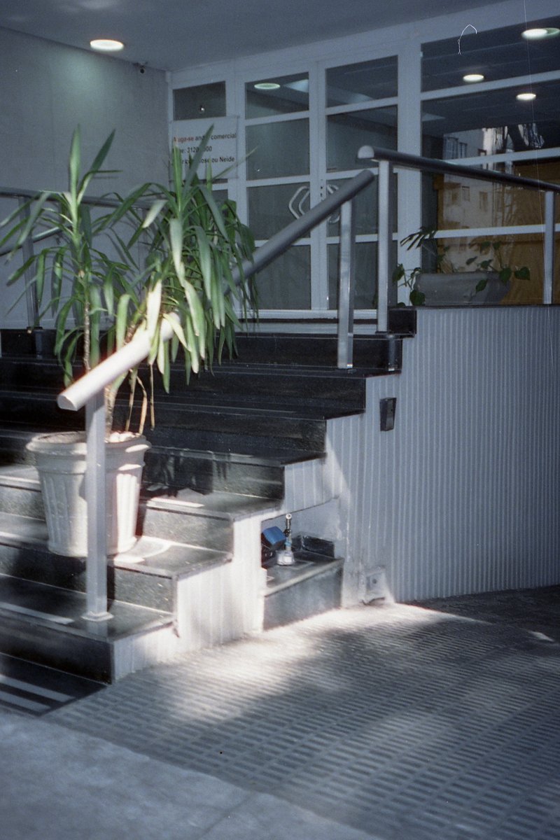 This is a color photo of the exterior of a building. It shows an entrance with several steps leading up to it. There is a metal handrail on the left s