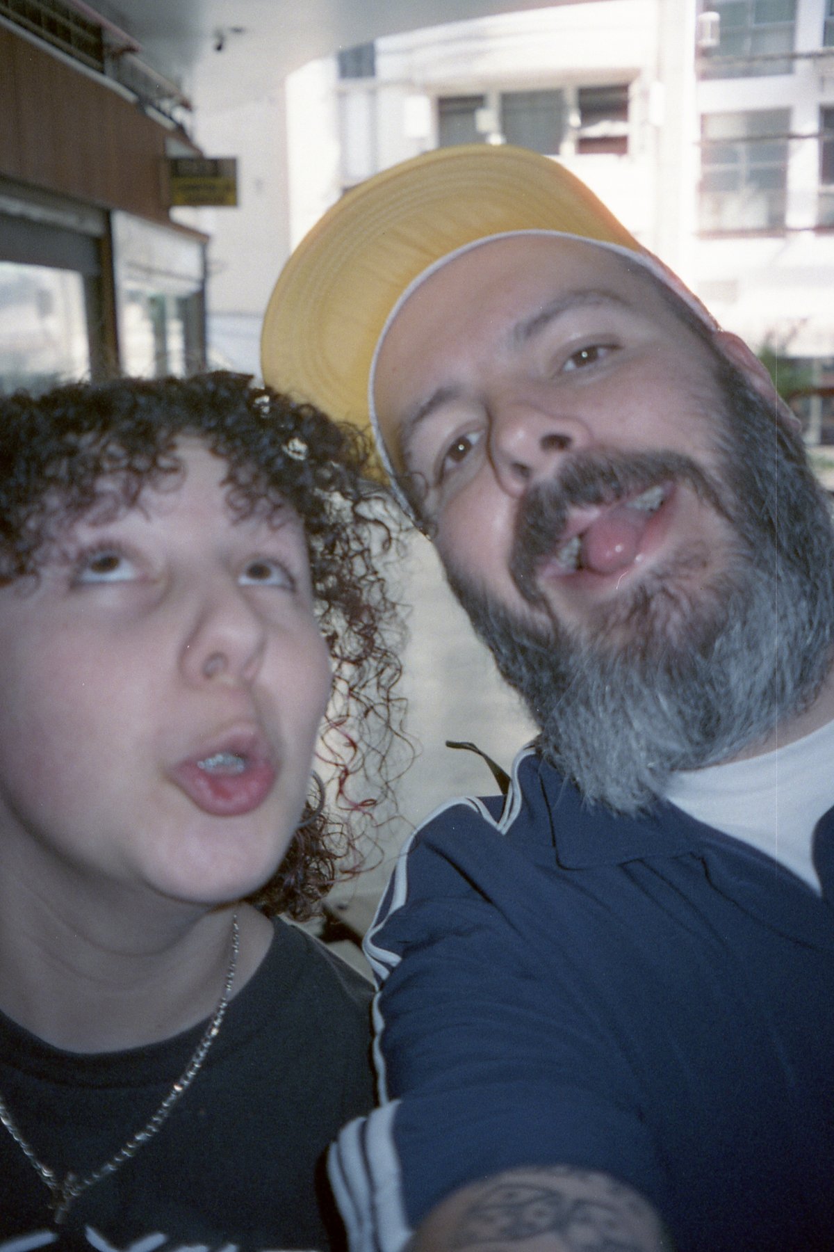This image captures a candid moment between two men. One man is making a playful face, his tongue sticking out in an exaggerated manner. He's wearing 