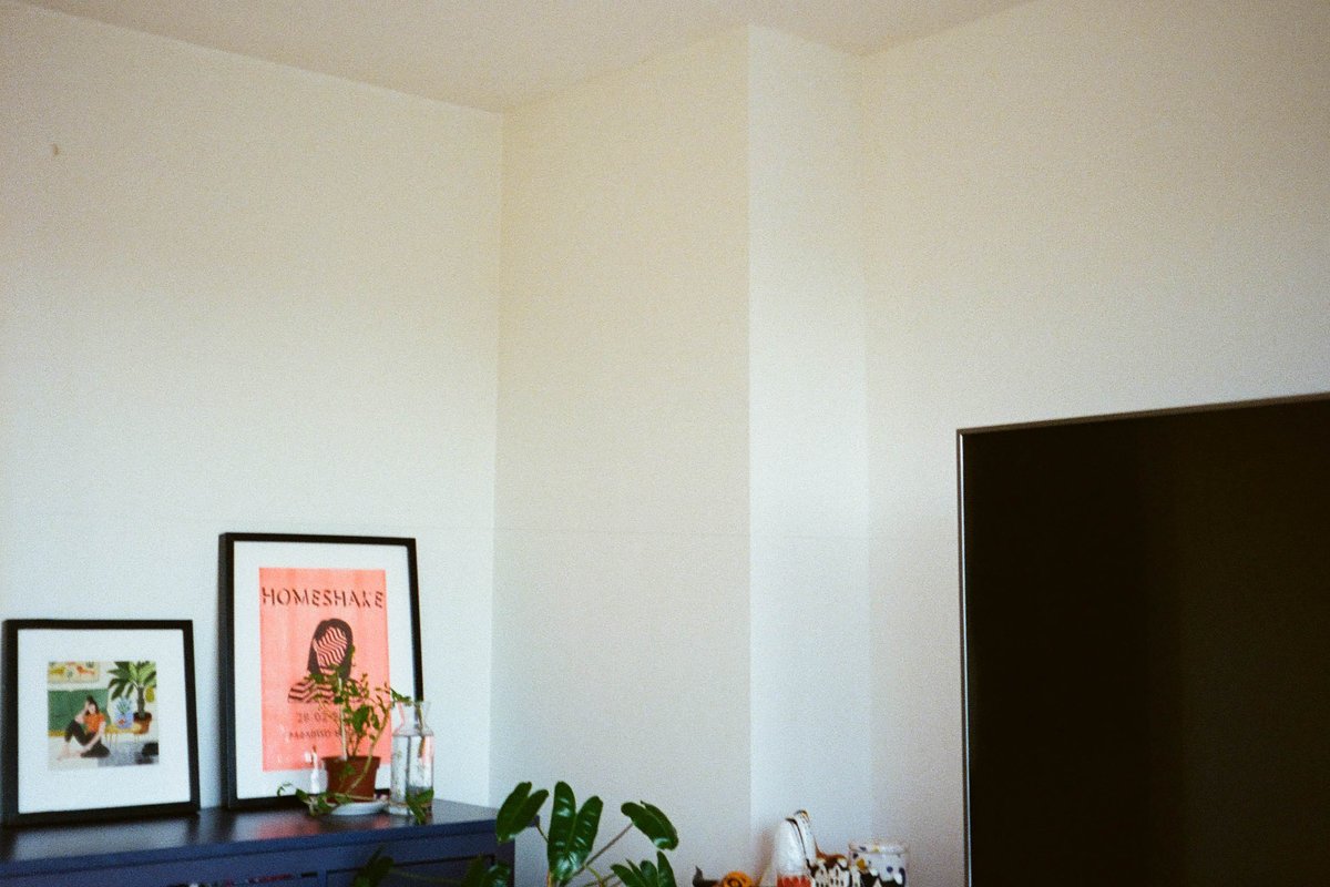 The image shows an interior space that appears to be a room within a home. The room is predominantly white and features a simple window with blinds pa