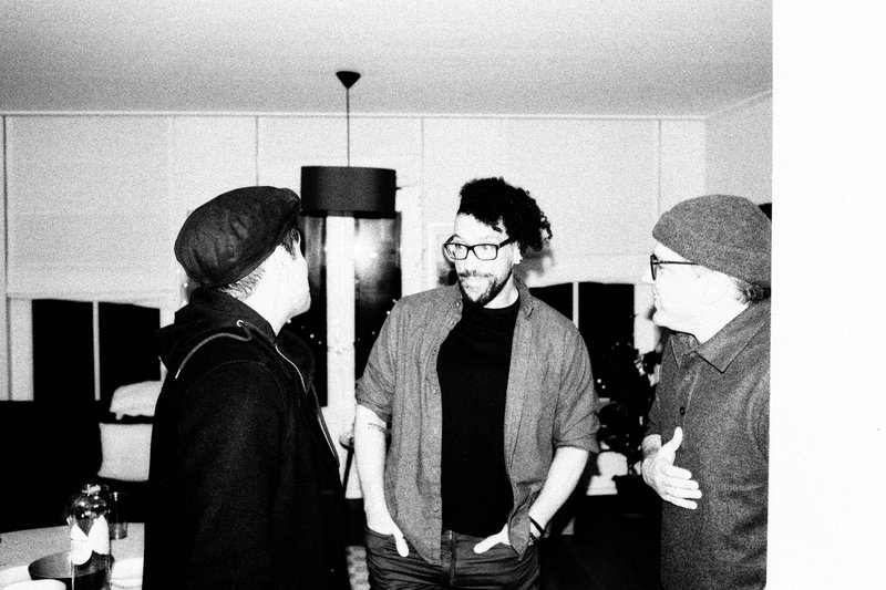 This is a split-style photo showing two separate moments with the same individuals. On the left, two people are standing together, engaged in conversa