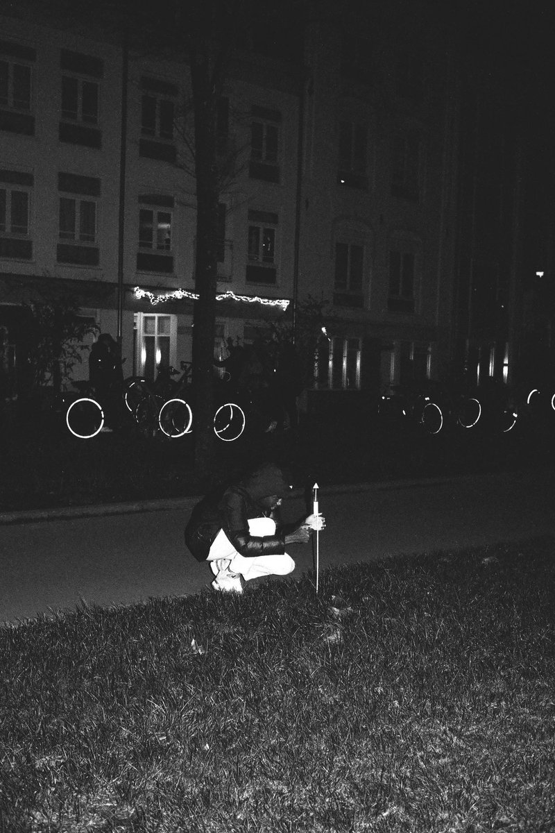 This is a black and white photo capturing an unusual scene. There are three people standing on the grass; two of them seem to be engaged with a small