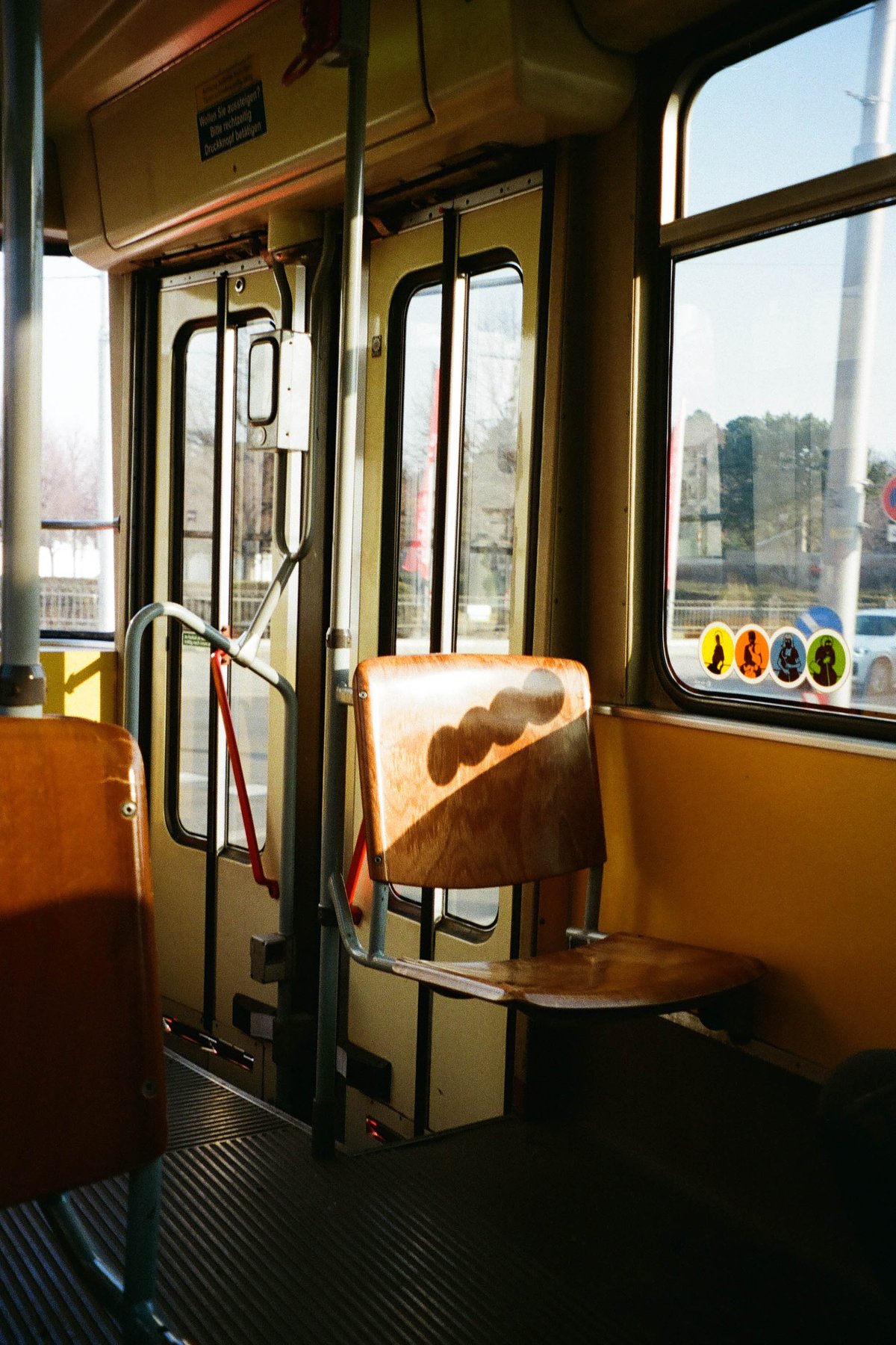 This image depicts an empty bus interior during daylight hours. The bus is predominantly yellow with various windows allowing natural light to fill the space. There's a row of seats on either side, and at one end of the bus, there's a bench. 